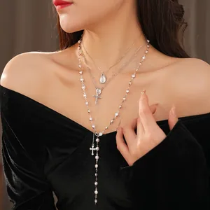 Layered pearl bead necklace with silver cross and portrait pendants on model
