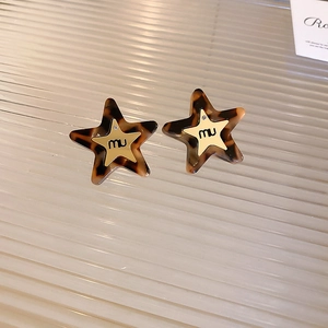 Close-up of star-shaped earrings with leopard print acetate and small crystal inlay