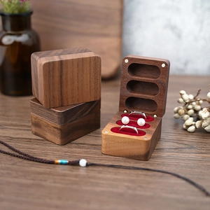 Close-up of walnut wood jewelry box with three slots and red velvet lining interior
