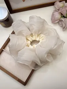Detailed close-up of ivory oversized mesh scrunchie on an elegant wooden frame