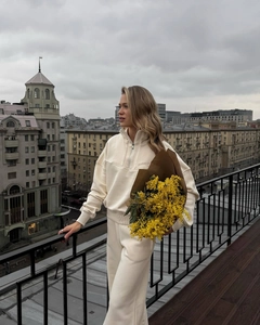 Detail of cream white half-zip sweatshirt and wide-leg jogger set on a balcony