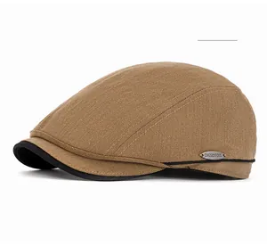 Detail of coffee herringbone flat cap with vintage metal logo plaque on side