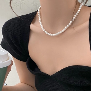 Close-up of elegant white pearl necklace on model's neck with black top contrast