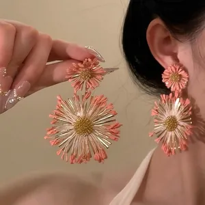 Détail de grandes boucles d'oreilles fleurs roses superposées avec accents dorés sur mannequin