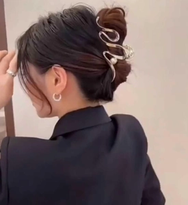 Silver streamline metal hair claw with pearl accent shown on a model hairstyle