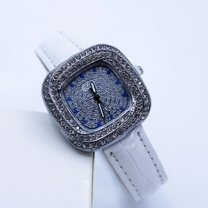 Close-up of square watch dial with blue and silver rhinestones on a white leather strap