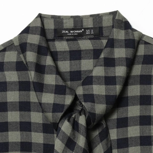 Close-up of green and black plaid shirt collar with ZEAL WOMAN brand label detail