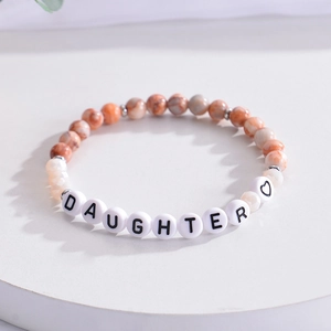 Macro view of stone bead bracelet with DAUGHTER letter beads and heart charm