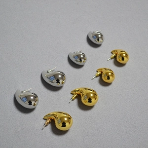 Detailed view of chunky hollow teardrop earrings in polished gold and silver finishes