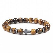Macro detail of natural tiger eye beads with a metallic cross and spacer on a beaded bracelet