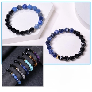 Detail of natural stone bracelets featuring lapis lazuli and obsidian on white geometric stand