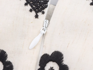 Detail view of cotton-linen dress with black floral embroidery and hidden zipper
