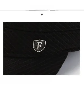 Detail of black winter flat cap featuring silver shield metal badge with F emblem