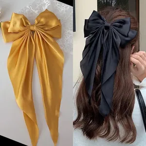Close-up of long satin ribbon bow hair clips in vibrant yellow and classic black