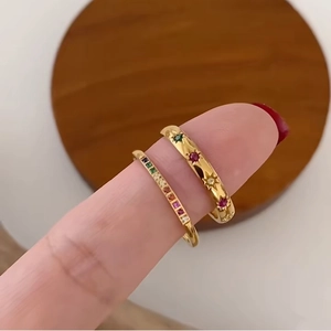 Detail of gold plated titanium rings with rainbow cubic zirconia on a wooden coaster
