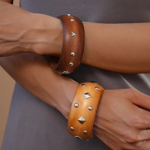 Close-up of vintage wooden bangles with star and geometric metal rivets on model arms