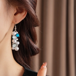 Primo piano di orecchini vintage con perle e perline blu indossati per un look retro lussuoso