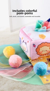 Detail of plush baby sensory tissue box toy with colorful pompoms and cartoon lion graphics