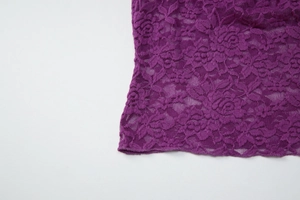 Gros plan détaillé du tissu en dentelle violette avec des motifs floraux ajourés