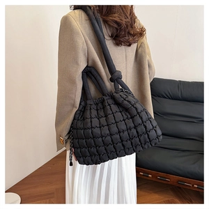 Detail of black quilted puffer bag showing drawstring closure and soft padded nylon texture