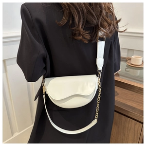 Detailed view of a white saddle crossbody bag with gold chain and wide shoulder strap
