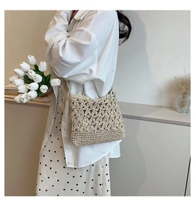 Detail shot of handwoven straw crossbody bag with intricate hollow flower pattern texture