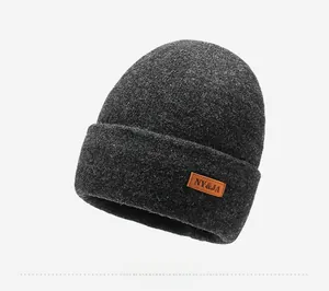 Detailed side view of dark grey thick knit beanie with leather brand logo patch