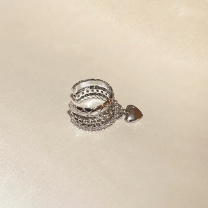 Detail of silver triple-layer ear cuff with zircon accents and heart pendant charm
