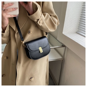 Classic black leather saddle bag with gold buckle worn with a stylish khaki trench coat