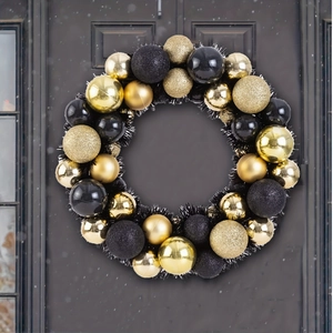 Detail of luxury black and gold Christmas wreath with glitter balls on a snowy door