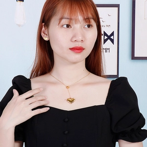 Golden heart-shaped necklace and earrings set shown on a female model with natural light