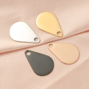 Detailed view of teardrop pendants in gold, silver, rose gold and black on pink silk