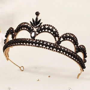 Detail of vintage gold crown with black crystals and beads on textured background