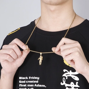 Detail of a 3D gold astronaut pendant necklace worn by a model on a black shirt
