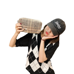 Grande trousse de maquillage en toile à carreaux tenue par un mannequin en tenue décontractée
