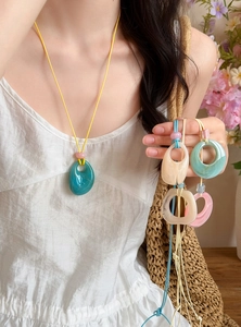 Close-up detail view showing various colorful marbled resin pendant necklaces for summer fashion