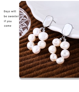 Macro detail of freshwater pearl hoop earrings with oval shell inlay on knit fabric