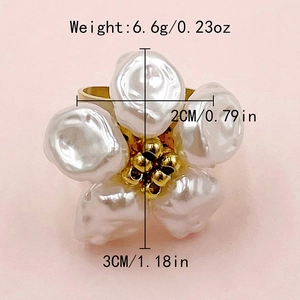 Detail view of flower ring with white pearls and golden beads on a soft pink surface