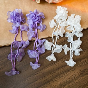 Detailed macro of chiffon flower tassel earrings with purple and white beads