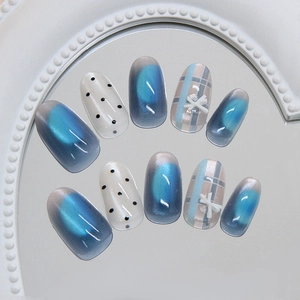 Blue cat eye press-on nails with bow, checkered pattern and polka dots on oval shapes