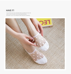 Detail of pink and white sheer heart polka dot invisible socks on a beige rug