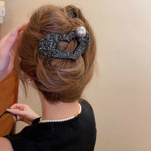 Close-up of heart-shaped hair claw clip with black crystals and large pearl detail