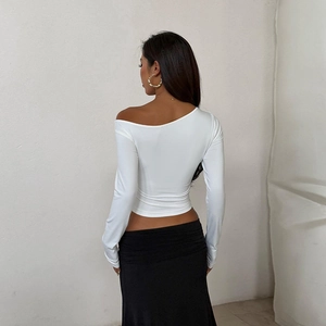 Dettaglio della maglia bianca a maniche lunghe scoperta sulle spalle con vestibilità slim