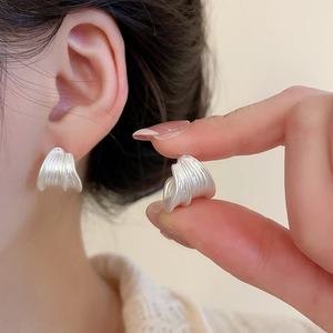 Detailed view of silver pleated earrings with vertical textures and a modern finish