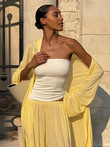Detail of yellow long cardigan and wide-leg trousers set with a cream tote bag