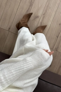 Posa piatta di un abito midi in maglia bianca abbinato a stivaletti scamosciati marroni
