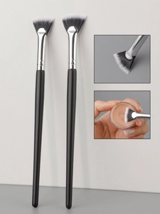 Detailed close-up of fan-shaped makeup brushes with soft bicolor bristles and slim black handles