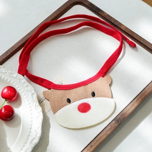 Detail of red knitted pet Christmas bib with reindeer motif on a rustic wooden tray
