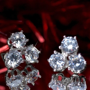 Macro-opname van geometrische zirkoon oorknopjes met zilveren klauwen en reflectie