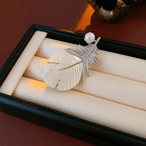 Macro detail of leaf brooch with mother of pearl, pavé zircons and a white pearl